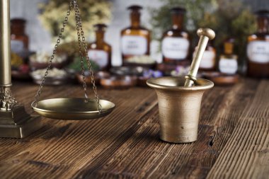 Doğal Tıp arka plan. Pirinç harç, şişe ve ölçek. Rustik tablo. Çeşitli kuru otlar kase. Bokeh.