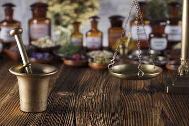 Doğal Tıp arka plan. Pirinç harç, şişe ve ölçek. Rustik tablo. Çeşitli kuru otlar kase. Bokeh.