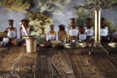 Doğal Tıp arka plan. Pirinç harç, şişe ve ölçek. Rustik tablo. Çeşitli kuru otlar kase. Bokeh.