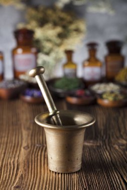 Doğal Tıp arka plan. Pirinç harç, şişe ve ölçek. Rustik tablo. Çeşitli kuru otlar kase. Bokeh.