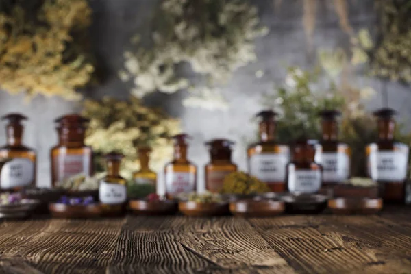 Natural medicine background. Brass mortar, bottles and scale. Rustic table. Assorted dry herbs in bowls. Bokeh.