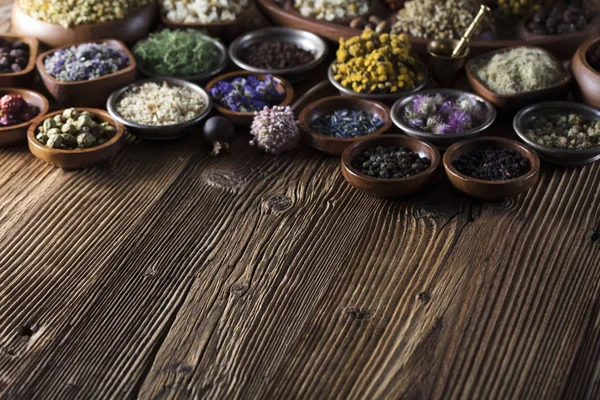 Alternative medicine. Herbs in bowls, mortar and medicine bottles on wooden rustic table.