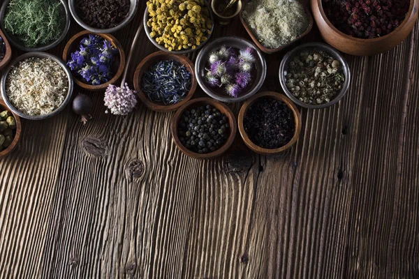 Alternative medicine. Herbs in bowls, mortar and medicine bottles on wooden rustic table.