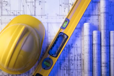 Mimarlık ve inşaat kavramı. Rulo planları, libela ve kask oluşturucu. 