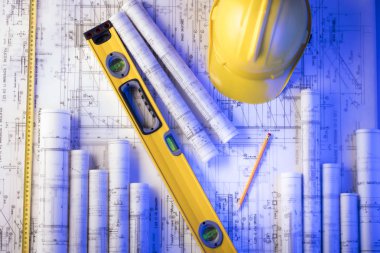 Mimarlık ve inşaat kavramı. Rulo planları, libela ve kask oluşturucu. 