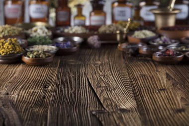 Doğal Tıp arka plan. Pirinç harç, şişe. Rustik tablo. Çeşitli kuru otlar kase. Bokeh.