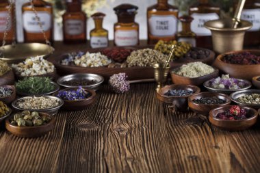 Doğal Tıp arka plan. Pirinç harç, şişe. Rustik tablo. Çeşitli kuru otlar kase. Bokeh.