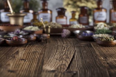 Doğal Tıp arka plan. Pirinç harç, şişe. Rustik tablo. Çeşitli kuru otlar kase. Bokeh.