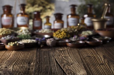 Doğal Tıp arka plan. Pirinç harç, şişe. Rustik tablo. Çeşitli kuru otlar kase. Bokeh.