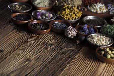 Doğal Tıp arka plan. Pirinç harç, şişe. Rustik tablo. Çeşitli kuru otlar kase. Bokeh.