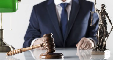  Yasal danışman. Beyaz masa ve arka plan üzerinde çekiç ve Themis heykeli.