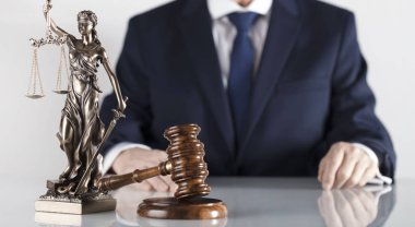  Yasal danışman. Beyaz masa ve arka plan üzerinde çekiç ve Themis heykeli.