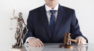 Yasal danışman. Beyaz masa ve arka plan üzerinde çekiç ve Themis heykeli.