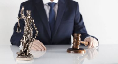  Yasal danışman. Beyaz masa ve arka plan üzerinde çekiç ve Themis heykeli.