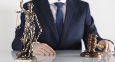  Yasal danışman. Beyaz masa ve arka plan üzerinde çekiç ve Themis heykeli.