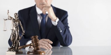  Yasal danışman. Beyaz masa ve arka plan üzerinde çekiç ve Themis heykeli.