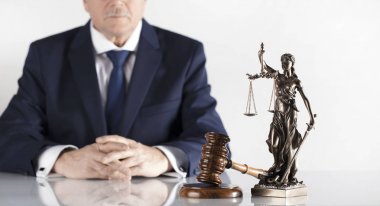  Yasal danışman. Beyaz masa ve arka plan üzerinde çekiç ve Themis heykeli.