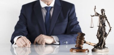  Yasal danışman. Beyaz masa ve arka plan üzerinde çekiç ve Themis heykeli.