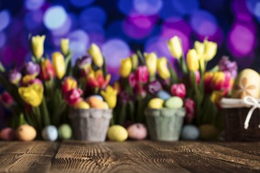 Paskalya Tema. Lale buketi. Paskalya yumurtaları. Renkli bokeh, tipografi ve logo için yer. Rustik ahşap masa. 