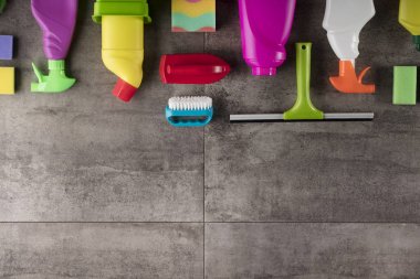 Bahar Temizlik kavramı. Temizleme ürünleri, gri döşeme üzerinde renkli. Tipografi için yer.