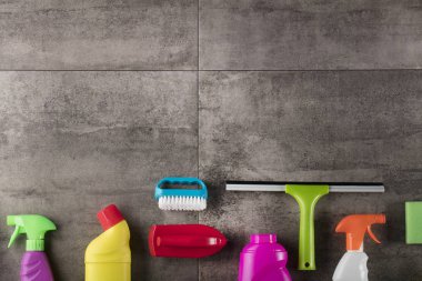 Bahar Temizlik kavramı. Temizleme ürünleri, gri döşeme üzerinde renkli. Tipografi için yer.
