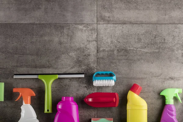 Spring cleaning concept. Colorful cleaning products on gray tiles. Place for typography.