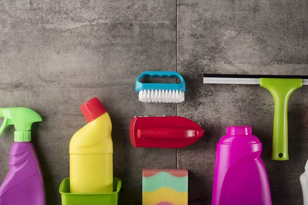 Spring cleaning concept. Colorful cleaning products on gray tiles. Place for typography.