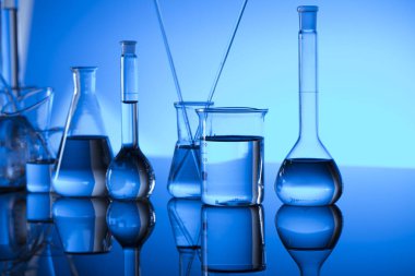 Bilim laboratuarı. Laboratuar kapkacakları, test tüpleri. Araştırma ve geliştirme. Mavi arka plan.