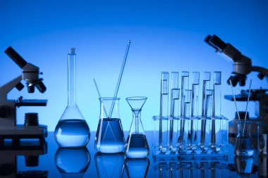 Bilim laboratuarı. Laboratuar kapkacakları, mikroskop, test tüpleri. Araştırma ve geliştirme. Mavi arka plan.