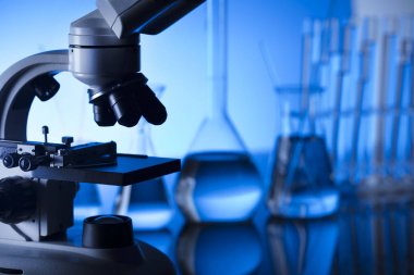 Bilim laboratuarı. Laboratuar kapkacakları, mikroskop, test tüpleri. Araştırma ve geliştirme. Mavi arka plan.