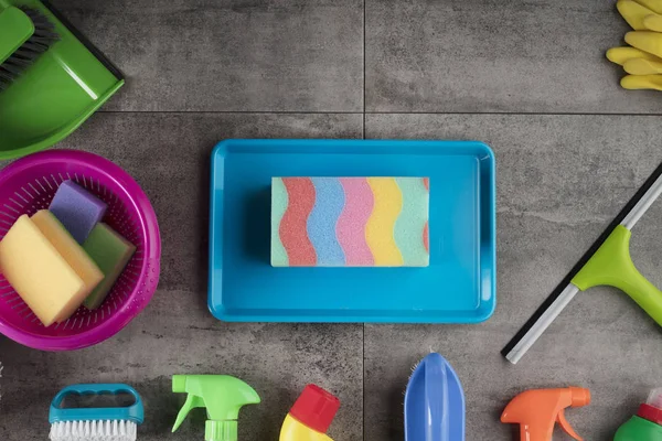 Spring cleaning concept. Colorful cleaning products on gray tiles. Place for typography.