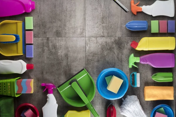 Spring cleaning concept. Colorful cleaning products on gray tiles. Place for typography.