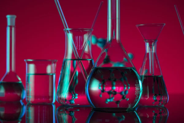 Chemical laboratory concept. Experiment with liquids.  Red background. Place for logo.
