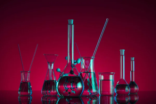 Chemical laboratory concept. Experiment with liquids.  Red background. Place for logo.