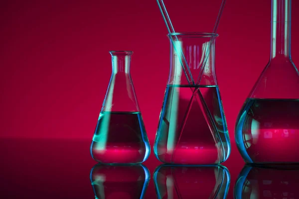 Chemical laboratory concept. Experiment with liquids.  Red background. Place for logo.