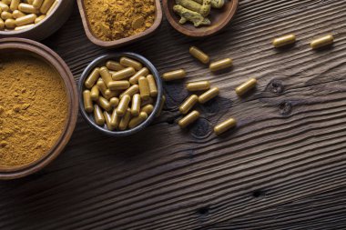 Curcuma kapsül, zerdeçal kökleri ve toz kase. Anti kanser ilaç. Ahşap masa. Üstten Görünüm vurdu.