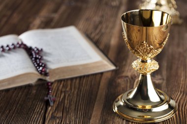 İlk Komünyon Tema. İncil'de, tespih ve ahşap masa üzerinde altın kadeh.