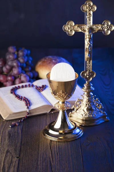 First holy communion theme. The Cross, Holy Bible, rosary and golden chalice. Bread and grapes  symbols of Christianity.