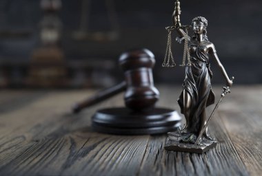 Adalet kavramı. Heykel ve yargıcın tokmağı kırsal ahşap masada ve karanlık arka planda..