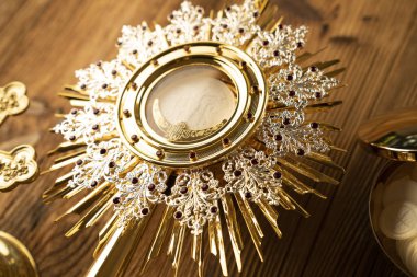 Roma Katolik Kilisesi teması. Haç, Kutsal İncil, Monstrance, rustik ahşap masada tespih ve altın kadeh.