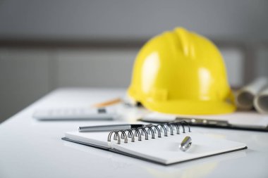 boş defter ve mimar masanın üstünde sarı kask