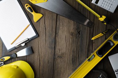 Ahşap masa arkaplanının her tarafında inşaat araçları olan alanı kopyala