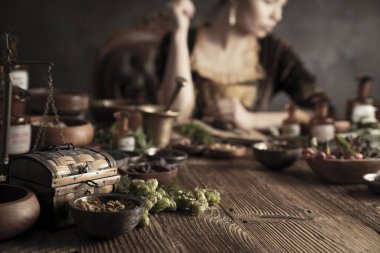 Doğal tıp konsepti. Antika eczacı, doğal ilaç hazırlıyor. Pirinç havan ve şişe. Kırsal masa. Çimli ve sade bitkiler vardır..