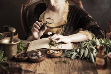 Doğal tıp konsepti. Antika eczacı, doğal ilaç hazırlıyor. Pirinç havan ve şişe. Kırsal masa. Çimli ve sade bitkiler vardır..