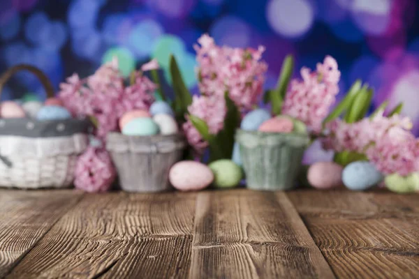 Easter background. Tulips and spring flowers. Easter eggs. Rustic wooden table. Pastel colors bokeh. Place for typography.