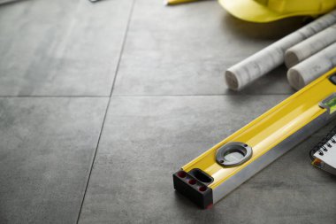 Müteahhit konsepti. Müteahhidin alet çantası: sarı başlık, karalama, el testeresi ve gri fayansların arkasındaki defter..