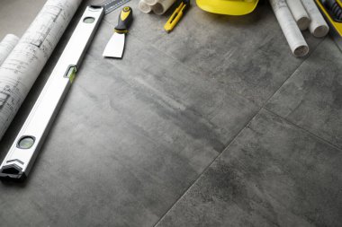 Müteahhit konsepti. Müteahhidin alet çantası: sarı başlık, karalama, el testeresi ve gri fayansların arkasındaki defter..