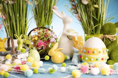 Paskalya teması. Paskalya süsleri. Sepet içinde paskalya yumurtaları ve lahana yaprağı. Bahar çiçeği buketi. Mavi arkaplan.