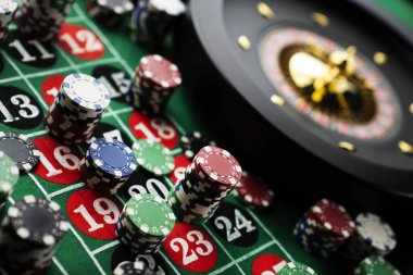 Kumarhanede rulet masası. Kumarhane, üzerinde kırmızı ve siyah sayılar olan yeşil bir masa hissetti. Poker fişleri yığını.