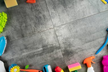 Bahar evi temizliği. Gri fayanslarda renkli temizlik seti. Üst görünüm.